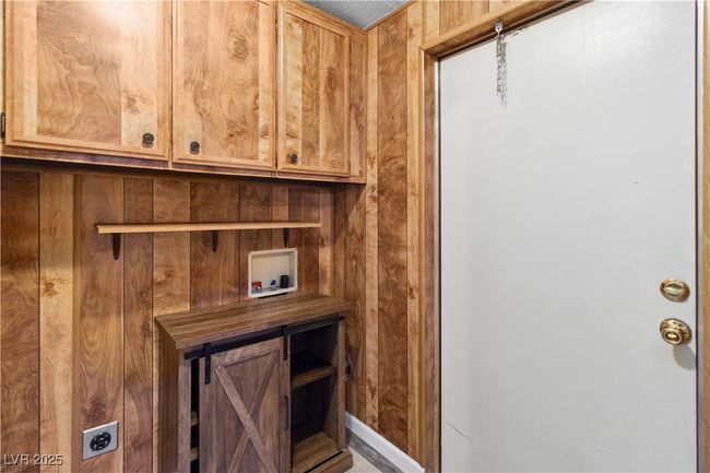 Laundry room with wood cabinets and door to attached carport parking. | Image 25