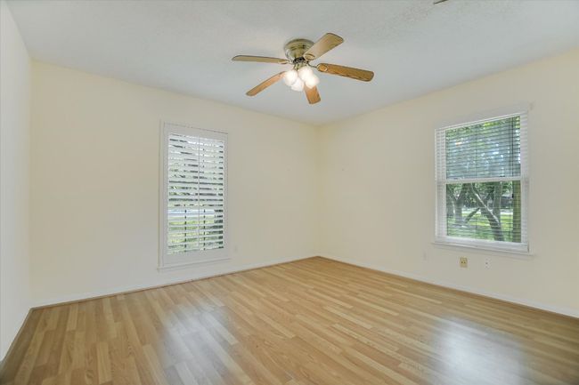 Empty room with plenty of natural light, light wood finished floors, baseboards, and a ceiling fan | Image 12
