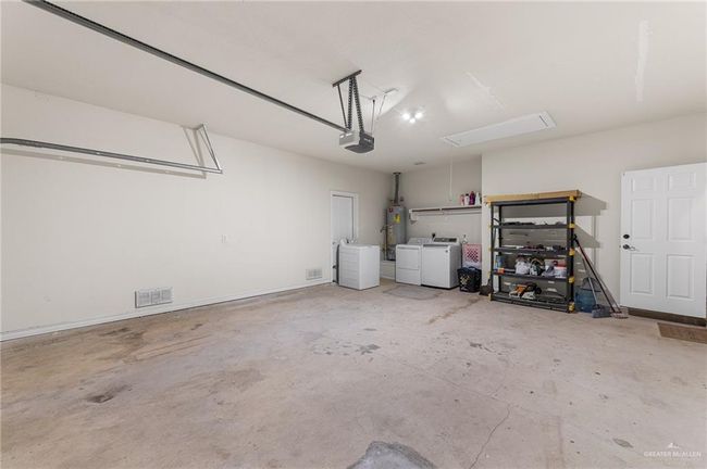 Garage featuring washer and clothes dryer, a garage door opener, and gas water heater | Image 6