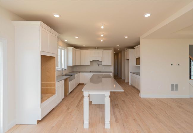 Kitchen with white cabinets, visible vents, light wood-style flooring, and a kitchen island | Image 8