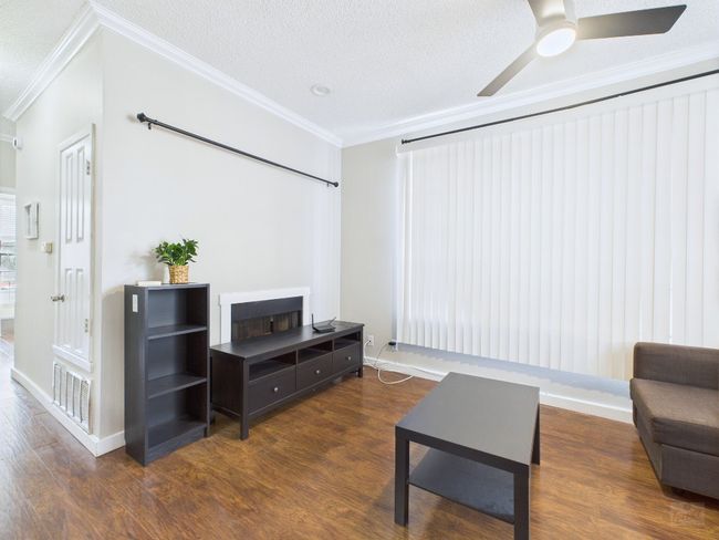 Living room with wood finished floors, crown molding, a ceiling fan, and a textured ceiling | Image 8