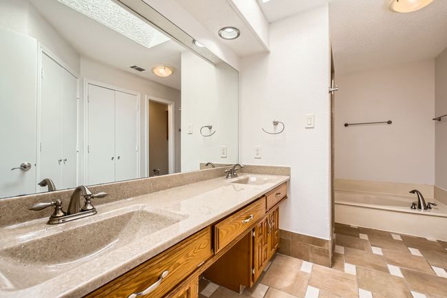 Primary Bath with double vanity, a garden tub, a skylight, and tile patterned floors | Image 14
