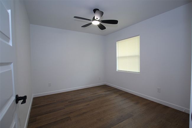 Empty room with a ceiling fan, baseboards, and dark wood finished floors | Image 8
