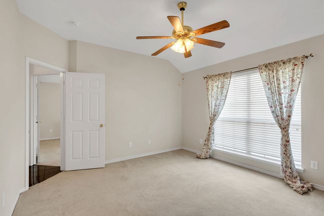 Carpeted spare room featuring lofted ceiling, a ceiling fan, and baseboards | Image 30