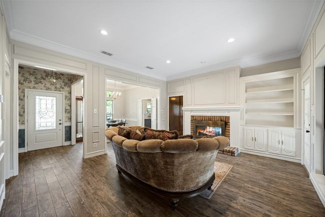 Living room with an inviting chandelier, visible vents, crown molding, and dark wood finished floors | Image 8