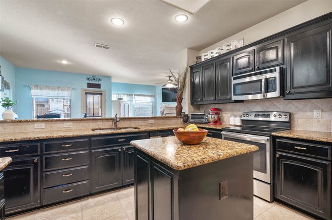 Kitchen with backsplash, appliances with stainless steel finishes, a sink, a kitchen island, and a peninsula | Image 14