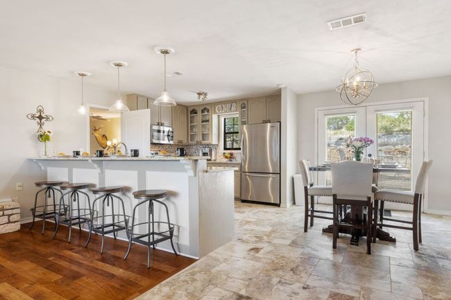 Kitchen with appliances with stainless steel finishes, a peninsula, a kitchen breakfast bar, glass insert cabinets, and a chandelier | Image 17