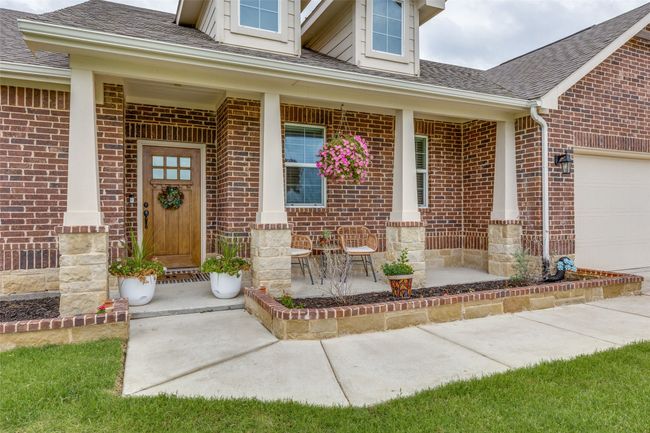 Entrance to property with covered porch, brick siding, and a shingled roof | Image 4