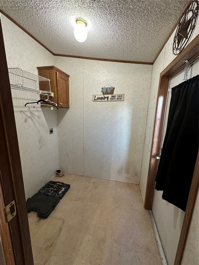 Laundry area with a textured ceiling, crown molding, light flooring, and hookup for an electric dryer | Image 31