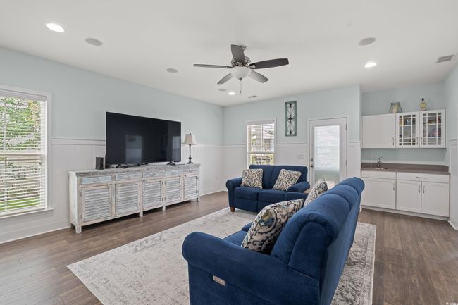 Living area on the first level featuring wainscoting, wet bar, speaker system, recessed lighting and an elevator. | Image 7