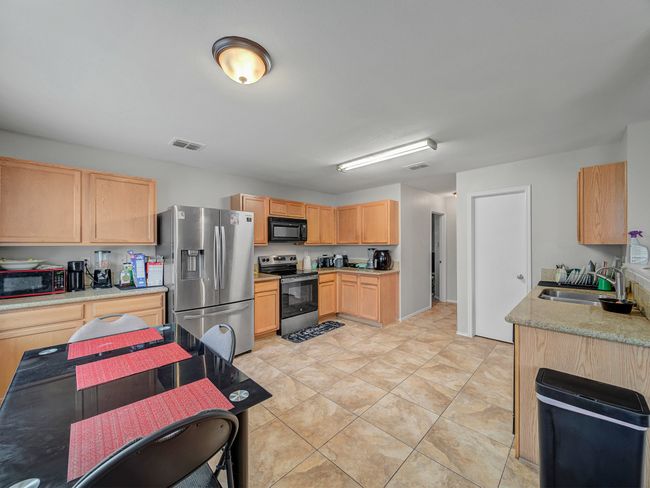 Kitchen with appliances with stainless steel finishes, a sink, light brown cabinetry, and light tile patterned floors | Image 8