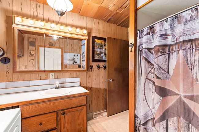 Bathroom with vanity, wooden ceiling, a shower with shower curtain, tile patterned floors, and wooden walls | Image 54
