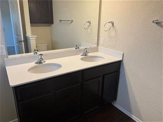 Bathroom with a textured wall and double vanity | Image 7