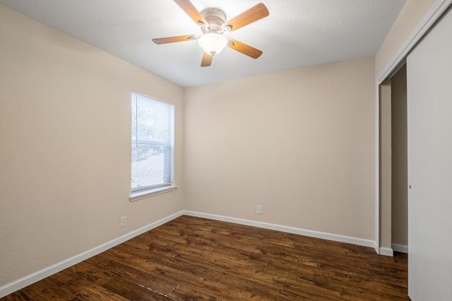 Unfurnished bedroom with dark wood-style floors, a closet, and ceiling fan | Image 12