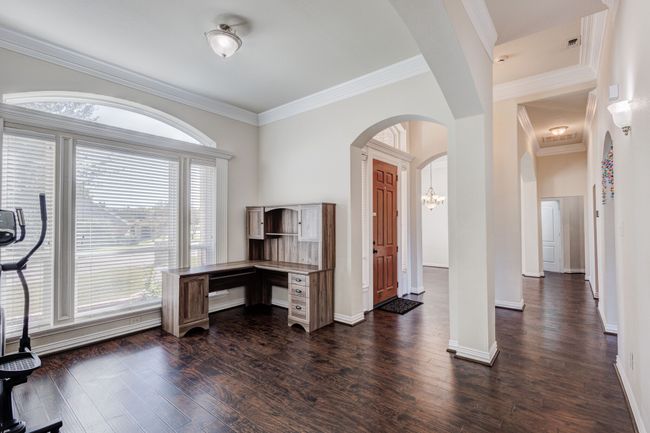 Office with dark hardwood / wood-style flooring, crown molding, and a notable chandelier | Image 12