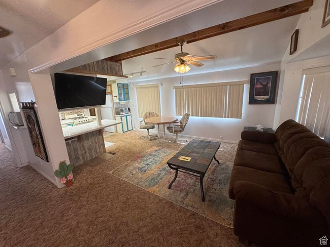 Carpeted living room with ceiling fan and beamed ceiling | Image 6