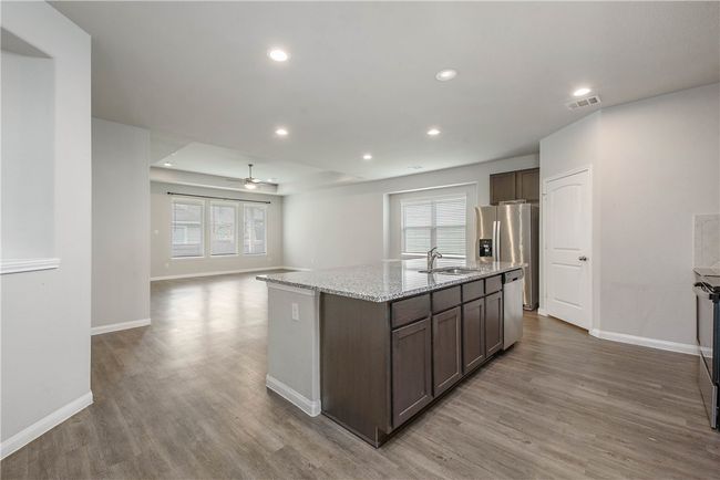 Kitchen with wood finished floors, ceiling fan, appliances with stainless steel finishes, a kitchen island with sink, and recessed lighting | Image 7