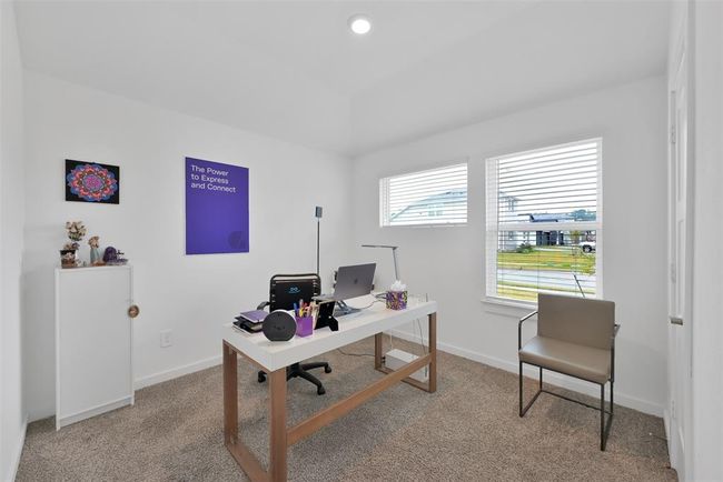 This photo showcases a bright and modern home office with a clean design. It features a sleek desk, ample natural light from two large windows, and neutral carpeting. The walls are adorned with minimal art, creating a calm and productive atmosphere. | Image 19