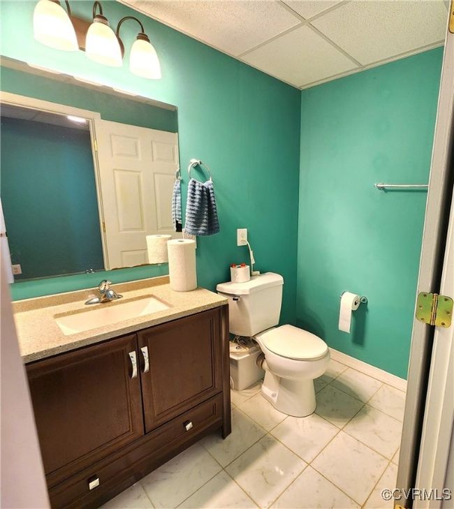 Bathroom with marble look tiles, vanity, and a paneled ceiling | Image 34