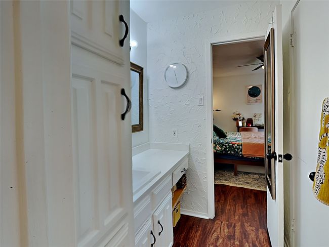 Bathroom featuring wood finished floors, vanity, ensuite bath, a textured wall, and a ceiling fan | Image 13