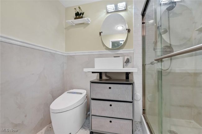 Bathroom featuring toilet, tile walls, wainscoting, a shower stall, and vanity | Image 26