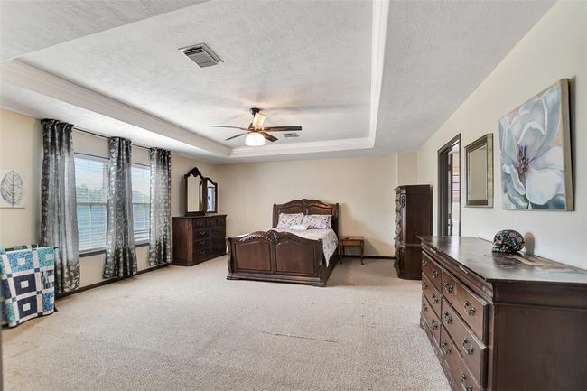 Spacious primary bedroom featuring an elegant tray ceiling. | Image 32