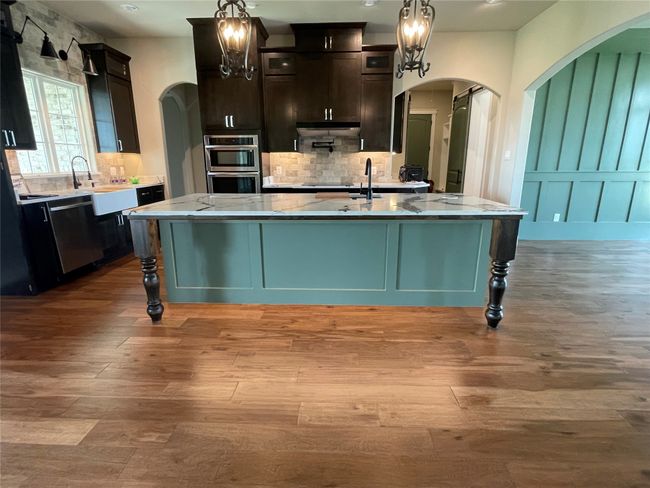 Kitchen featuring arched walkways, backsplash, dishwasher, light wood-type flooring, and recessed lighting | Image 17