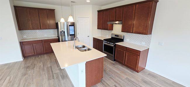Kitchen featuring appliances with stainless steel finishes, under cabinet range hood, tasteful backsplash, light wood finished floors, and recessed lighting | Image 8