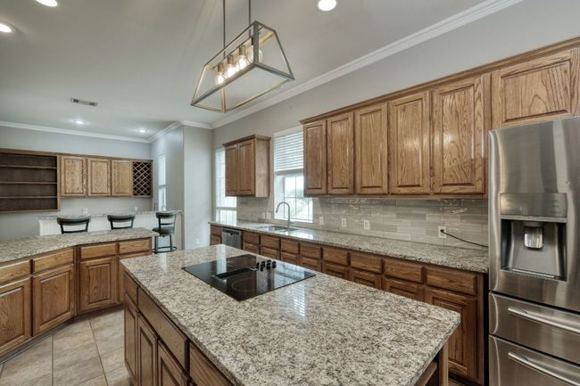 Kitchen featuring open shelves, brown cabinetry, stainless steel appliances, and a sink | Image 14