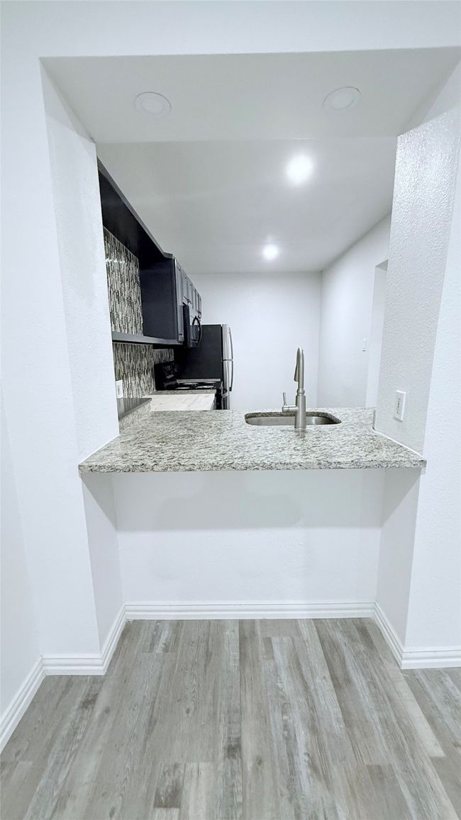 Kitchen featuring a sink, stove, wood finished floors, and a peninsula | Image 4