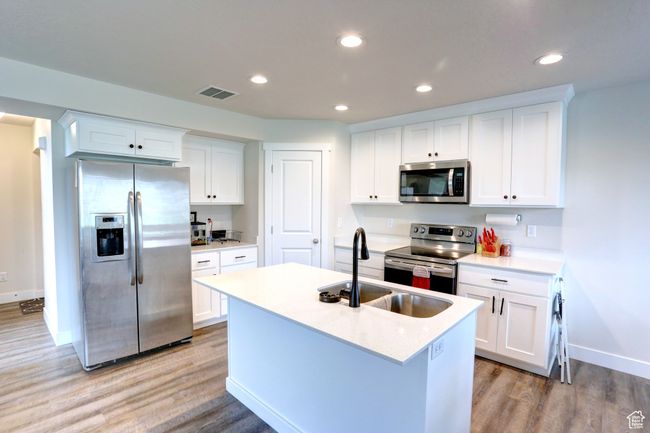 Kitchen with a sink, visible vents, light wood-style flooring, baseboards, and appliances with stainless steel finishes | Image 5