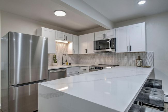 Kitchen featuring white cabinets, a peninsula, appliances with stainless steel finishes, and a sink | Image 15