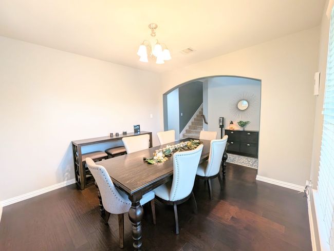 Dining area with arched walkways, a chandelier, dark wood-style floors, and stairway | Image 15