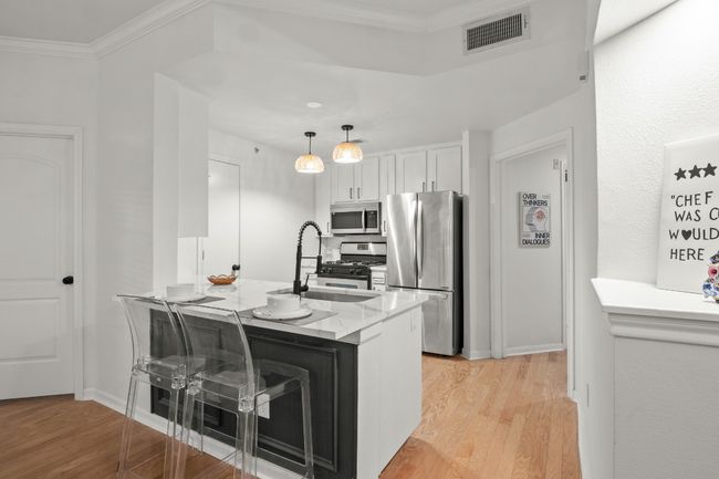 Kitchen, stainless steel appliances, crown molding, light wood-style floors, and a sink | Image 7