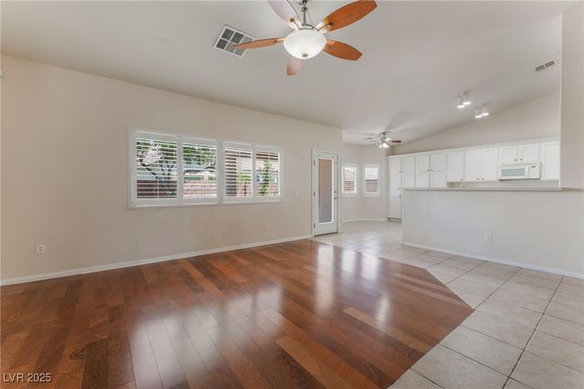 Unfurnished living room featuring ceiling fan, lofted ceiling, baseboards, and light wood-style flooring | Image 7