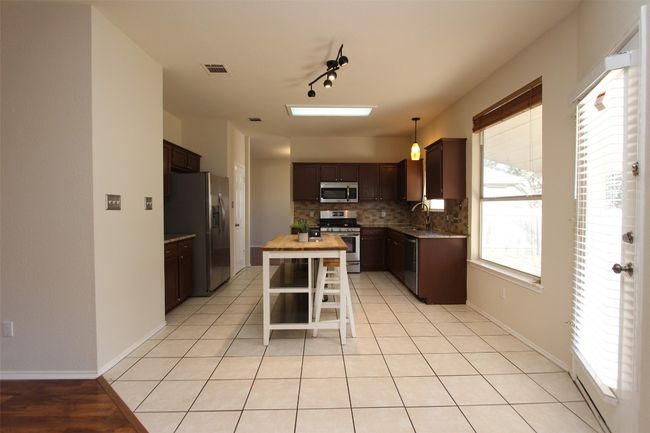 Kitchen with stainless steel appliances, decorative backsplash, dark brown cabinetry, and a kitchen island | Image 4