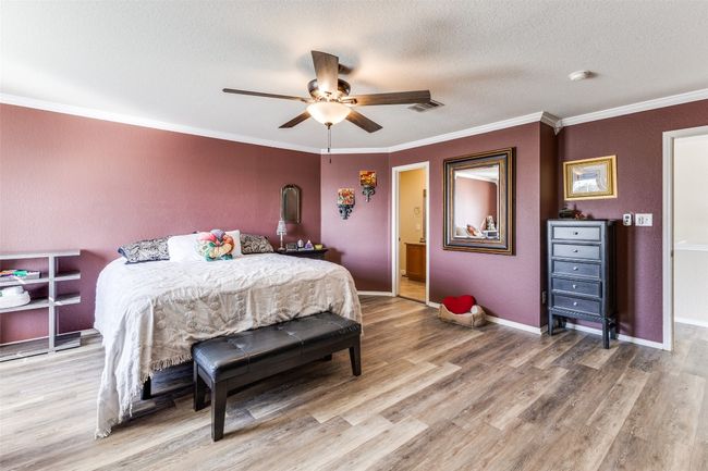 Bedroom with light wood finished floors, crown molding, a textured ceiling, a ceiling fan, and baseboards | Image 28