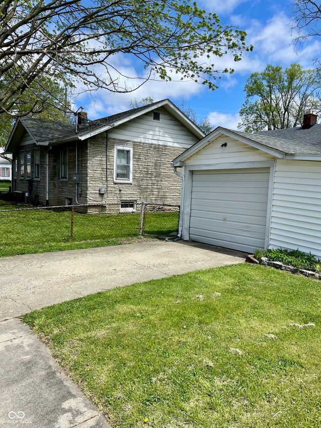 view of home's exterior featuring concrete driveway, a chimney, an outbuilding, fence, and a yard | Image 29