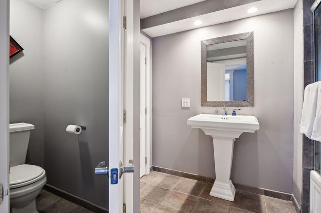 Spacious lower-level bath offers separate cammode, stylish pedestal sink, large tub/shower with tile surround. | Image 27