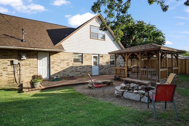 Back of property featuring a gazebo, an outdoor fire pit, a wooden deck, a shingled roof, and brick siding | Image 27