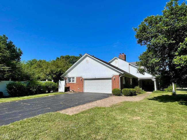 view of home's exterior with a chimney, a yard, brick, an attached garage, and driveway | Image 8
