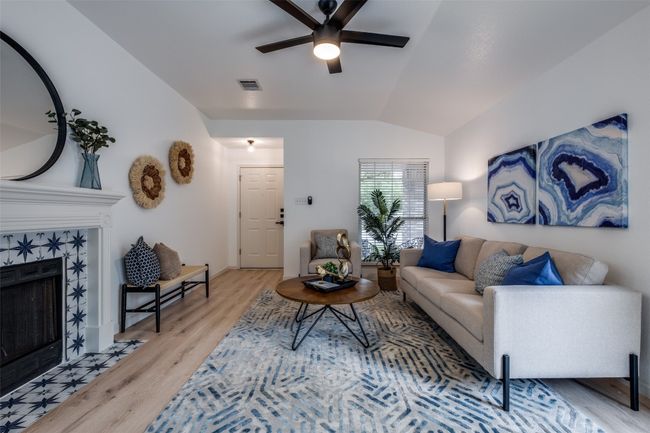 Living room with vaulted ceiling, a fireplace, visible vents, ceiling fan, and wood finished floors | Image 5