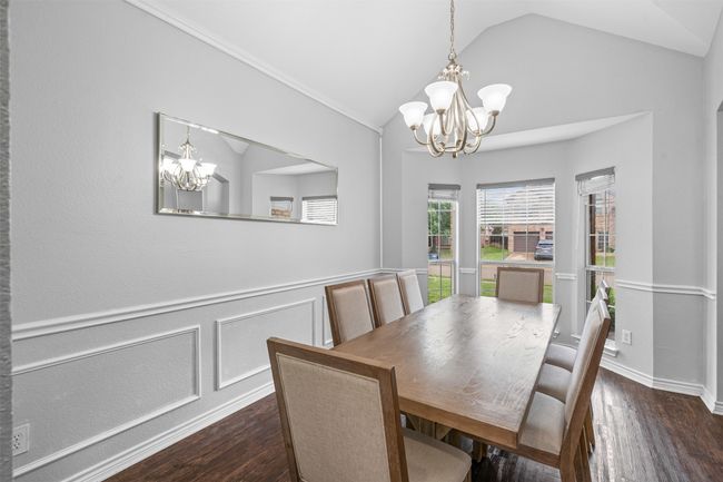 Dining space featuring a chandelier, lofted ceiling, laminate floors, and a wainscoted wall | Image 9