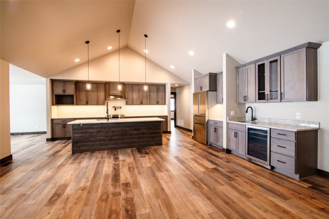 Kitchen featuring sink, decorative light fixtures, stainless steel refrigerator, beverage cooler, and a kitchen island with sink | Image 8