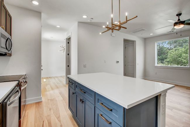 Kitchen with stainless steel range, light wood-type flooring, a center island, light countertops, and recessed lighting | Image 8
