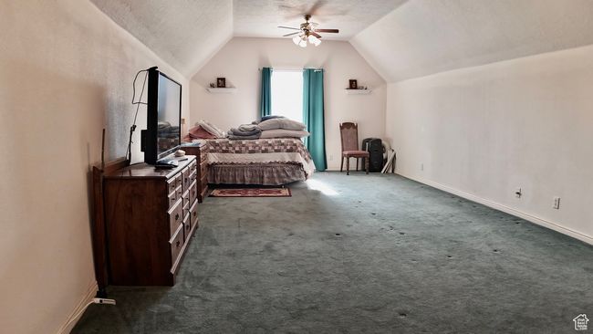 Bedroom with baseboards, a ceiling fan, carpet, a textured ceiling, and vaulted ceiling | Image 44