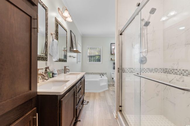 Bathroom featuring crown molding, a stall shower, wood finished floors, toilet, and a bathtub | Image 16