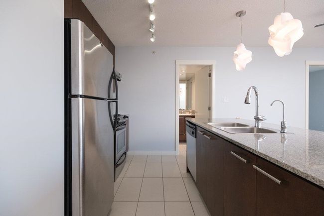 Kitchen with dark brown cabinetry, a sink, pendant lighting, appliances with stainless steel finishes, and light tile patterned floors | Image 6