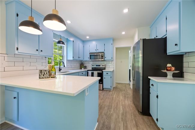 Kitchen featuring a peninsula, a sink, backsplash, blue cabinetry, and appliances with stainless steel finishes | Image 15