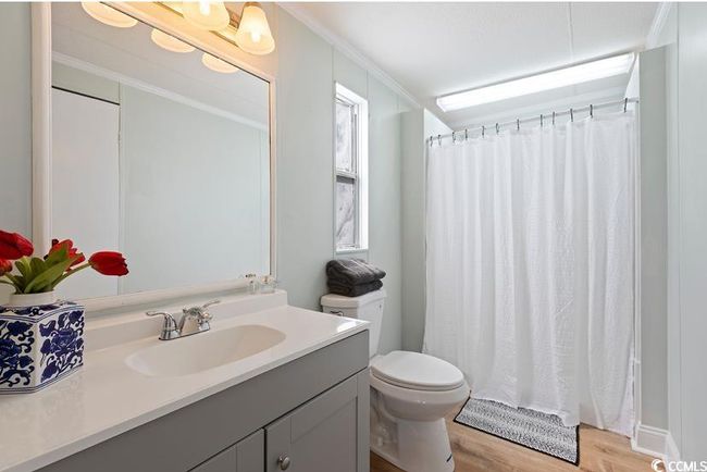 Full bath with vanity, toilet, wood finished floors, ornamental molding, and curtained shower | Image 22